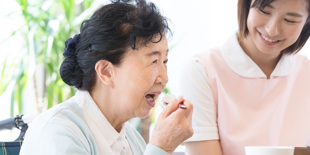 食事をする高齢者と見守る介護士