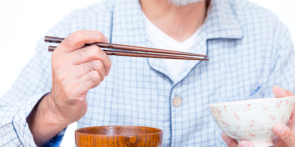 箸とお茶碗を持つ高齢者