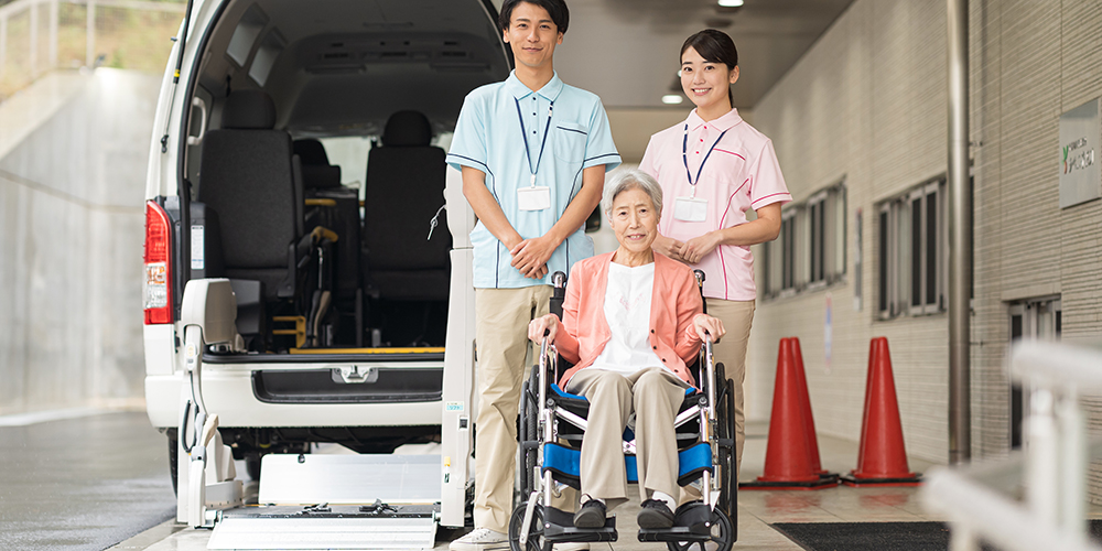 水色とピンクのポロシャツを着ている介護職員と車椅子のシニア女性