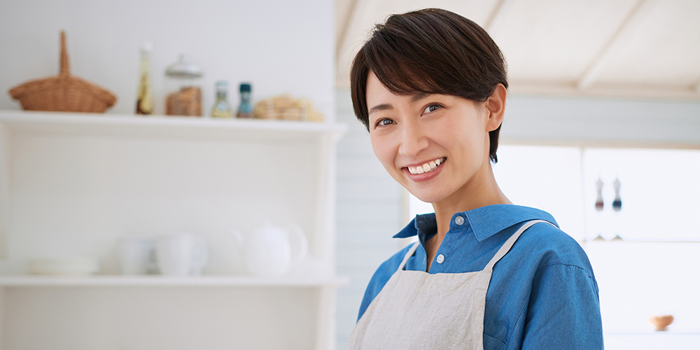 キッチンに立つ笑顔の主婦イメージ